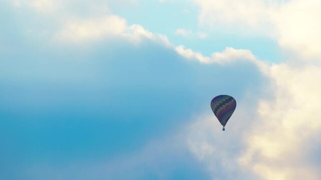 Aerial view of colorful hot air balloon flying against the scenic cloudy blue sky. Beautiful blue sky with clouds in the background. Daytime footage. High-quality 4K video. 