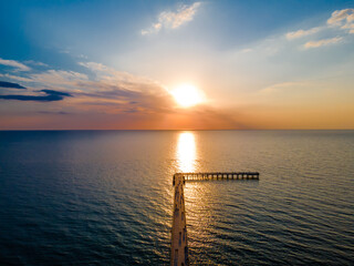 Aerial view of a bridge to sea and a sunset in horizon