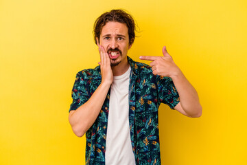 Young caucasian man isolated on yellow background having a strong teeth pain, molar ache.