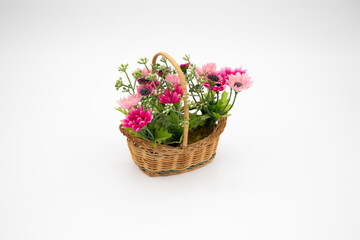 Handmade colorful synthetic flowers in closeup basket isolated on white background and copy space