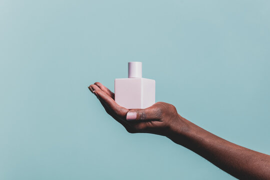 Black Female Hand Holds Nail Polish Jar On Orange Background