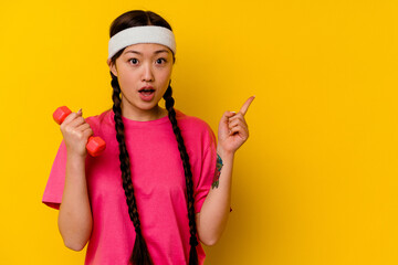 Fototapeta na wymiar Young sport chinese woman isolated on yellow background pointing to the side