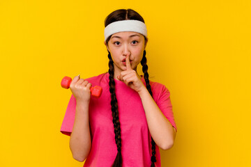 Young sport chinese woman isolated on yellow background keeping a secret or asking for silence.