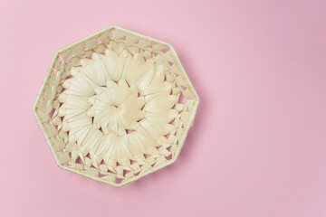Octagonal wicker straw basket on a pink background. View from above. Decorative interior items