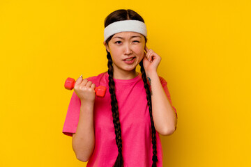 Fototapeta na wymiar Young sport chinese woman isolated on yellow background covering ears with hands.