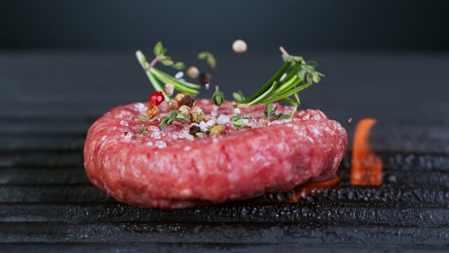 Super Slow Motion Shot of Falling Fresh Beef Hamburger Meat with Herbs on Grill at 1000 fps.
