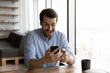 Excited young Caucasian man use cellphone feel euphoric win online lottery on gadget. Happy male...