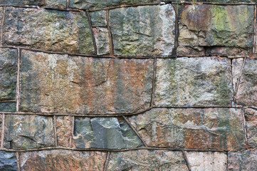 Old weathered wall made of granite stones, abstract background.