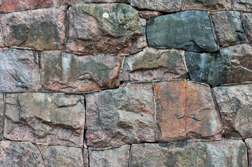 Old weathered wall made of granite stones, abstract background.