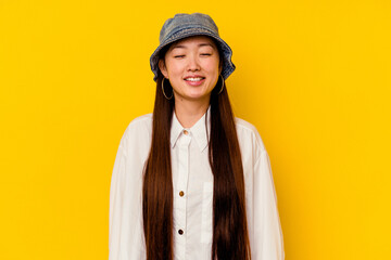 Young chinese woman isolated on yellow background laughs and closes eyes, feels relaxed and happy.