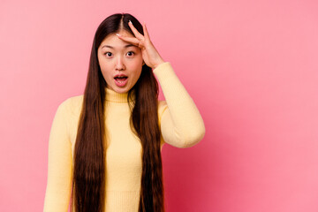 Young chinese woman isolated on pink background shouts loud, keeps eyes opened and hands tense.