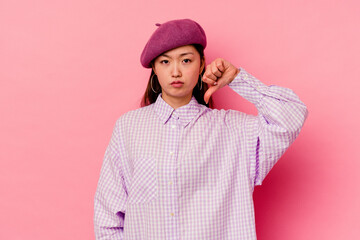 Young chinese woman isolated on pink background showing a dislike gesture, thumbs down. Disagreement concept.
