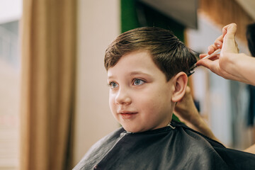 Haircut for little kid boy, professional barber doing haircut. Hairdress for children