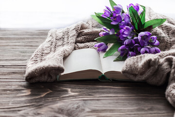 Cozy morning. Opened book and a bouquet of flowers on a wooden background with copy space. Cozy home interior, lifestyle, romantic atmosphere.