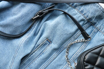 Naklejka premium A close look at part of a denim jacket and a black purse with a chain