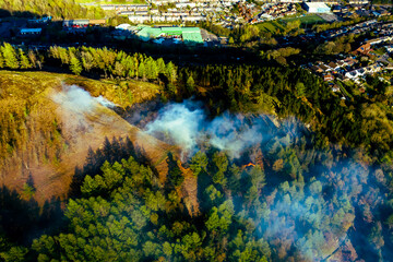 Aerial View of forest area on fire in valley casused by kids starting fires during hot weather.