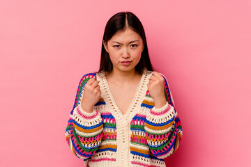 Young chinese woman isolated on pink background showing fist to camera, aggressive facial expression.