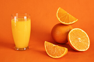 Fresh orange juice in glass and orange slices.Orange background.Monochromatic food photography.