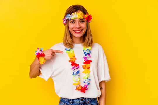 Young caucasian woman celebrating a hawaiian party isolated on yellow background person pointing by hand to a shirt copy space, proud and confident