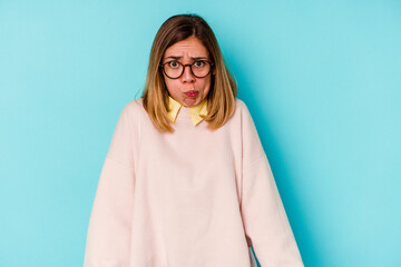 Fototapeta premium Young student caucasian woman isolated on blue background blows cheeks, has tired expression. Facial expression concept.