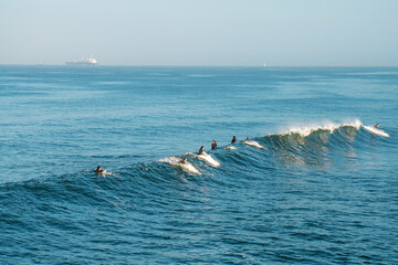 Surfers catch a wave in the Pacific ocean on the coast. Los Angeles, USA - 14 Apr 2021