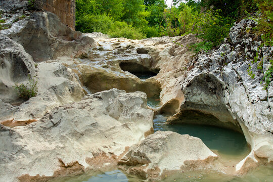 Mirna river flows, forming waterfalls and hollowing cauldron-like forms in stone