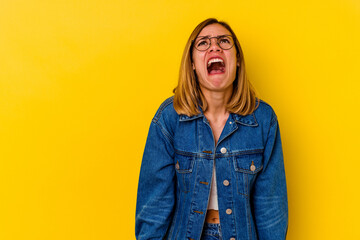 Young caucasian skinny woman isolated on yellow background shouting very angry, rage concept,...