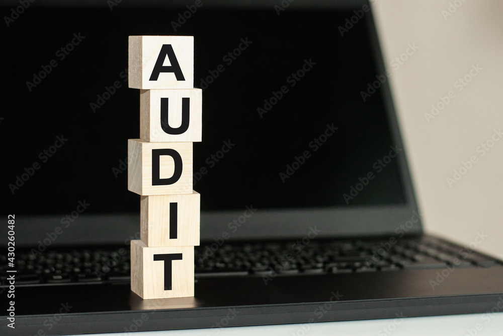 Aufkleber audit word made with building blocks on the black keyboard. a row of wooden cubes with a word writte