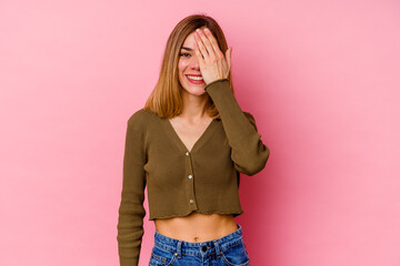 Young caucasian woman isolated on pink background having fun covering half of face with palm.