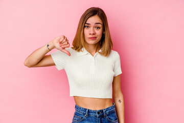 Young caucasian woman isolated on pink background showing thumb down, disappointment concept.