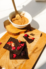  Chocolate bar with strawberries on wooden board with white bowl with cocoa powder and wooden spoon
