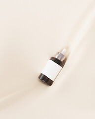 Mockup glass dropper bottle for cosmetics, care products or advertising, on beige linen cloth. 3d illustration render