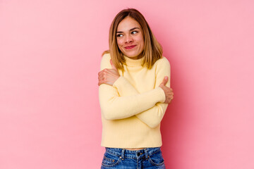 Young caucasian woman isolated on pink background hugs, smiling carefree and happy.