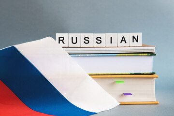 the inscription russian on a stack of textbooks, books, exercise books and national flag of Russia,...