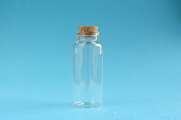 Empty glass bottle with cork cap on blue background. Close-up, horizontal photo.