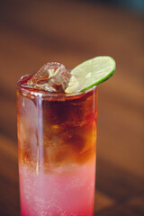rum and coke with rhubarb craft cocktail served with ice and lime 