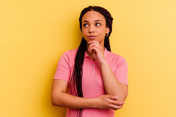 Young african american woman isolated on yellow background thinking and looking up, being reflective, contemplating, having a fantasy.