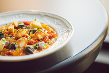 tomato based seafood meal served in a decorative and elegant white dish