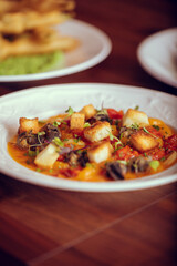 tomato based seafood meal served in a decorative and elegant white dish