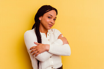 Young african american woman isolated on yellow background hugs, smiling carefree and happy.
