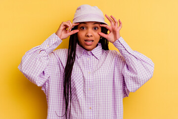Young african american woman isolated on yellow background keeping eyes opened to find a success opportunity.