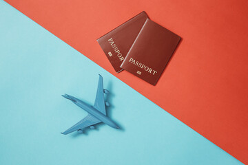 A blue passenger plane and passport stands on a colorful background. The concept of travel and transportation.