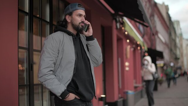 Young, modern handsome man talking on the phone of sunny spring day.