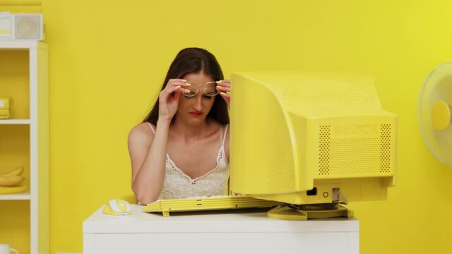 Young Woman, Manager, Is Working At Yellow Retro PC, Feeling Tired, Putting Eyeglasses Off To Relieve Stress, Suffering From Computer Eye Strain, Office Work Issues, Slow Motion.