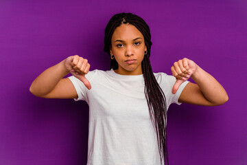 Young african american woman isolated on yellow background showing a dislike gesture, thumbs down....