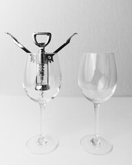 Vertical shot of two empty glasses with a wine bottle opener inside