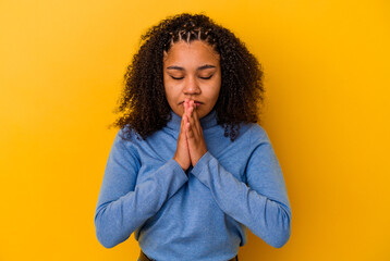 Young african american woman isolated on yellow background praying, showing devotion, religious...