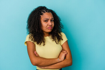 Young african american woman isolated on blue background blows cheeks, has tired expression. Facial...