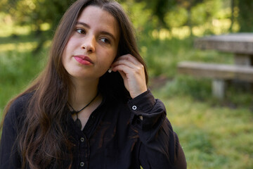 long-haired, fair-skinned woman putting on white wireless headphones in nature. teenager using...