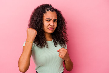 Young african american woman isolated on pink background showing fist to camera, aggressive facial...